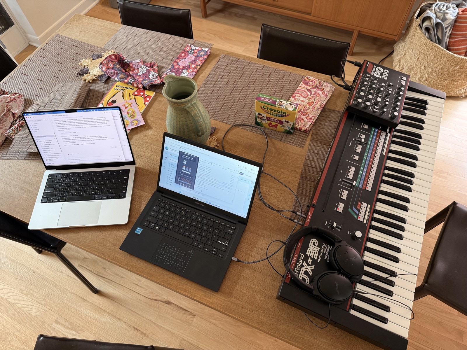 MacBook and ASUS Vivobook side by side on the dining table, both connected to a Roland JX-3P synthesizer with PG-200 programmer on top.